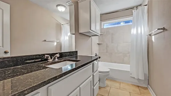 a bathroom with a granite countertop sink a toilet a mirror and bathtub