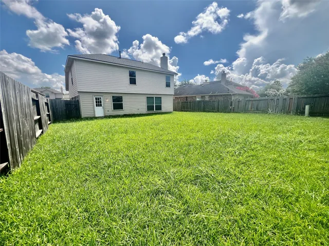 a view of a house with a big yard potted plants and large tree