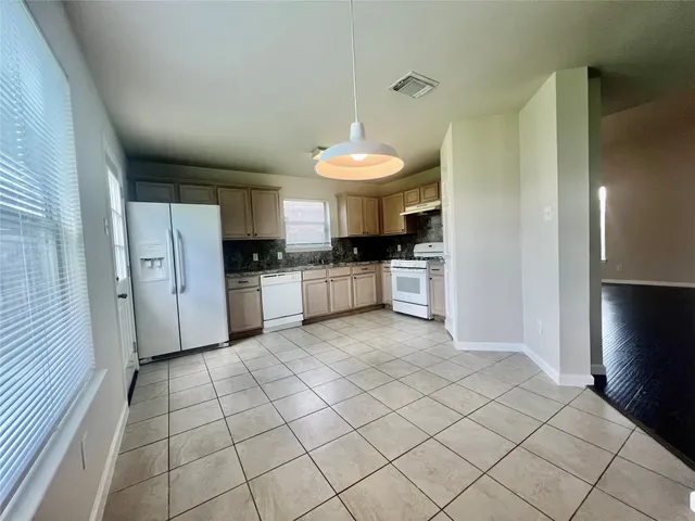 a kitchen with granite countertop a refrigerator and a stove top oven