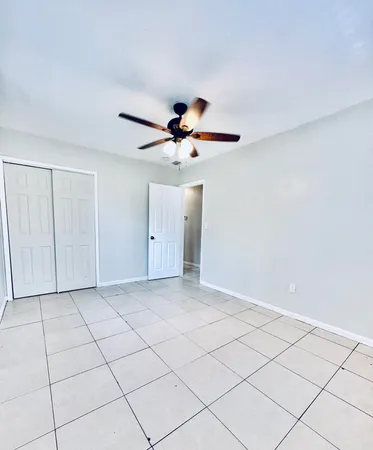 a view of an empty room and chandelier fan
