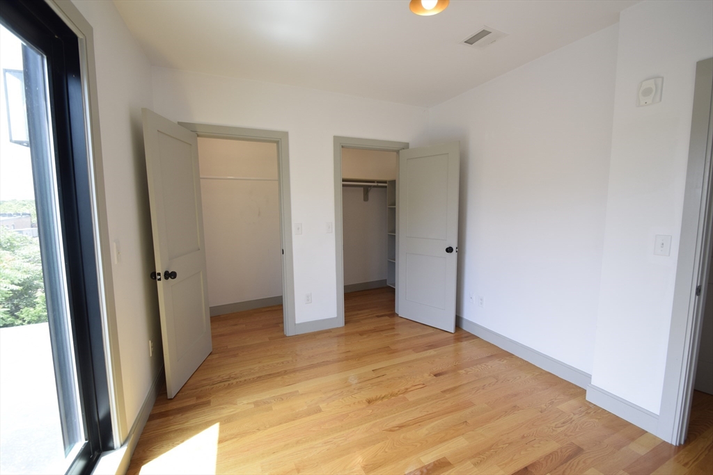 15 Maywood Street, Unit 4 Boston, MA 02119 - Photo 11 of 14 an empty room with closet and wooden floor