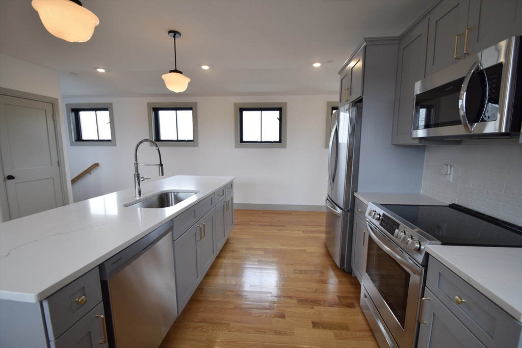 15 Maywood Street, Unit 4 Boston, MA 02119 - Photo 4 of 14 a kitchen with stainless steel appliances granite countertop a sink a stove and a wooden floors