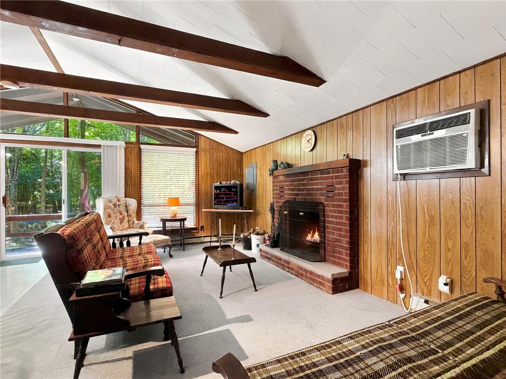 116 Aspen Road Albrightsville, PA 18210 - Photo 11 of 33 Exposed wood beams and a brick fireplace create a cozy cabin aesthetic in this living room.