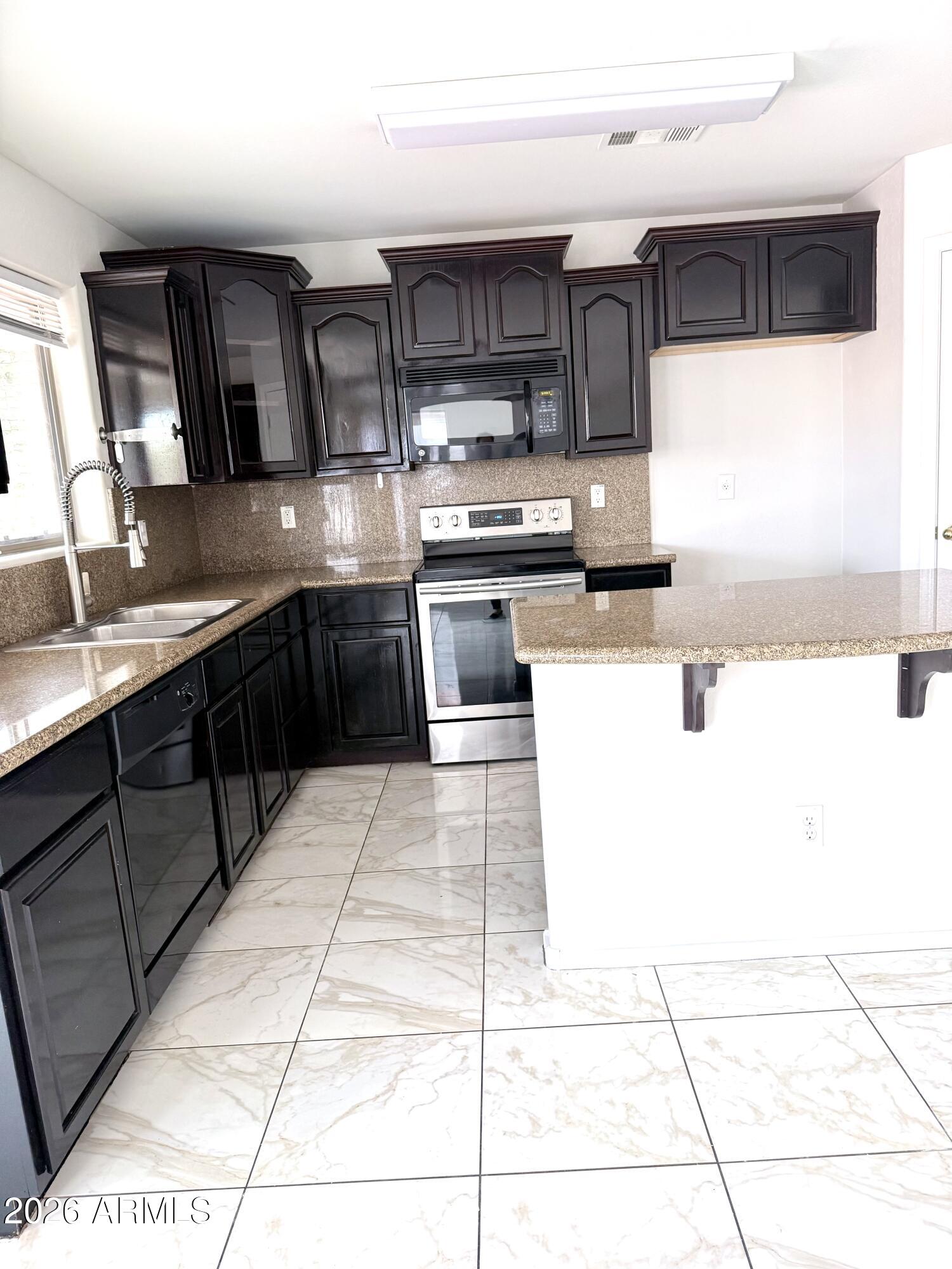 2326 West Gaby Road Phoenix, AZ 85041 - Photo 23 of 75 a kitchen with stainless steel appliances kitchen island granite countertop a stove a sink and a microwave