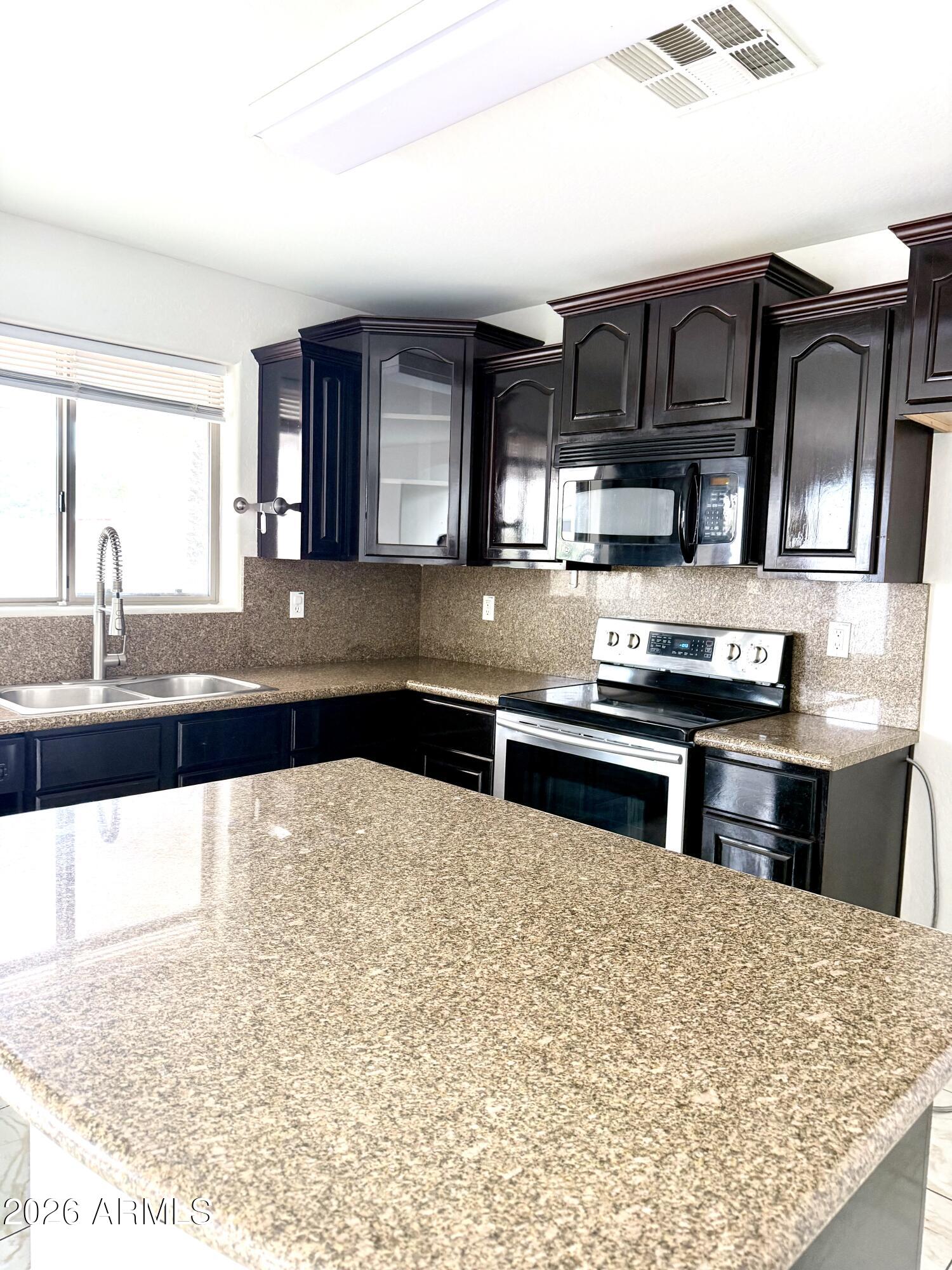 2326 West Gaby Road Phoenix, AZ 85041 - Photo 27 of 75 a kitchen with stainless steel appliances granite countertop a stove and a sink