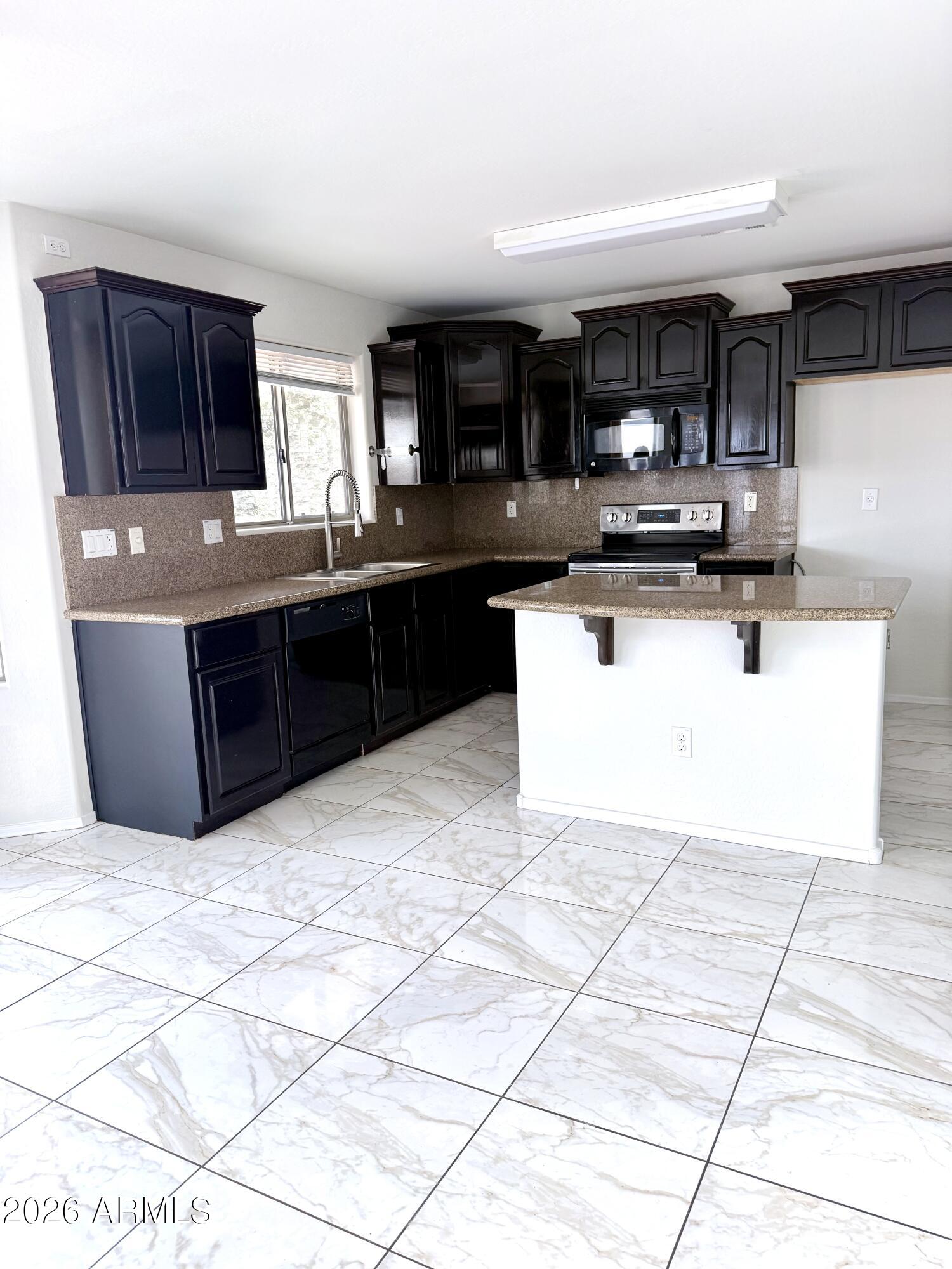 2326 West Gaby Road Phoenix, AZ 85041 - Photo 28 of 75 a kitchen with stainless steel appliances kitchen island granite countertop a sink and cabinets