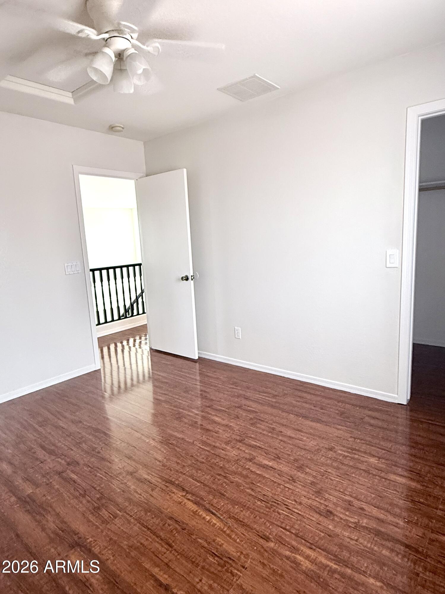 2326 West Gaby Road Phoenix, AZ 85041 - Photo 43 of 75 a view of an empty room with wooden floor and a chandelier