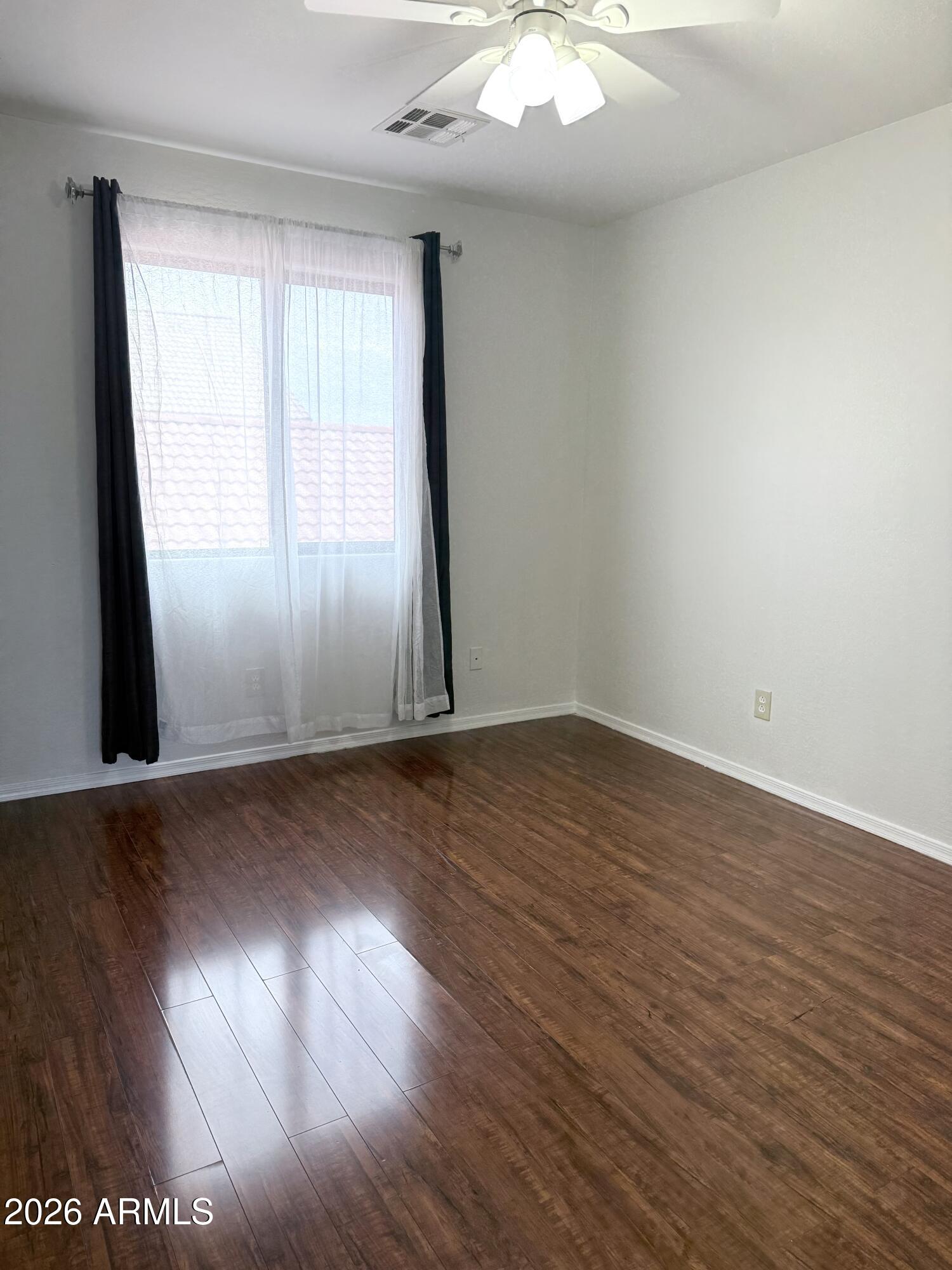 2326 West Gaby Road Phoenix, AZ 85041 - Photo 56 of 75 an empty room with wooden floor and windows