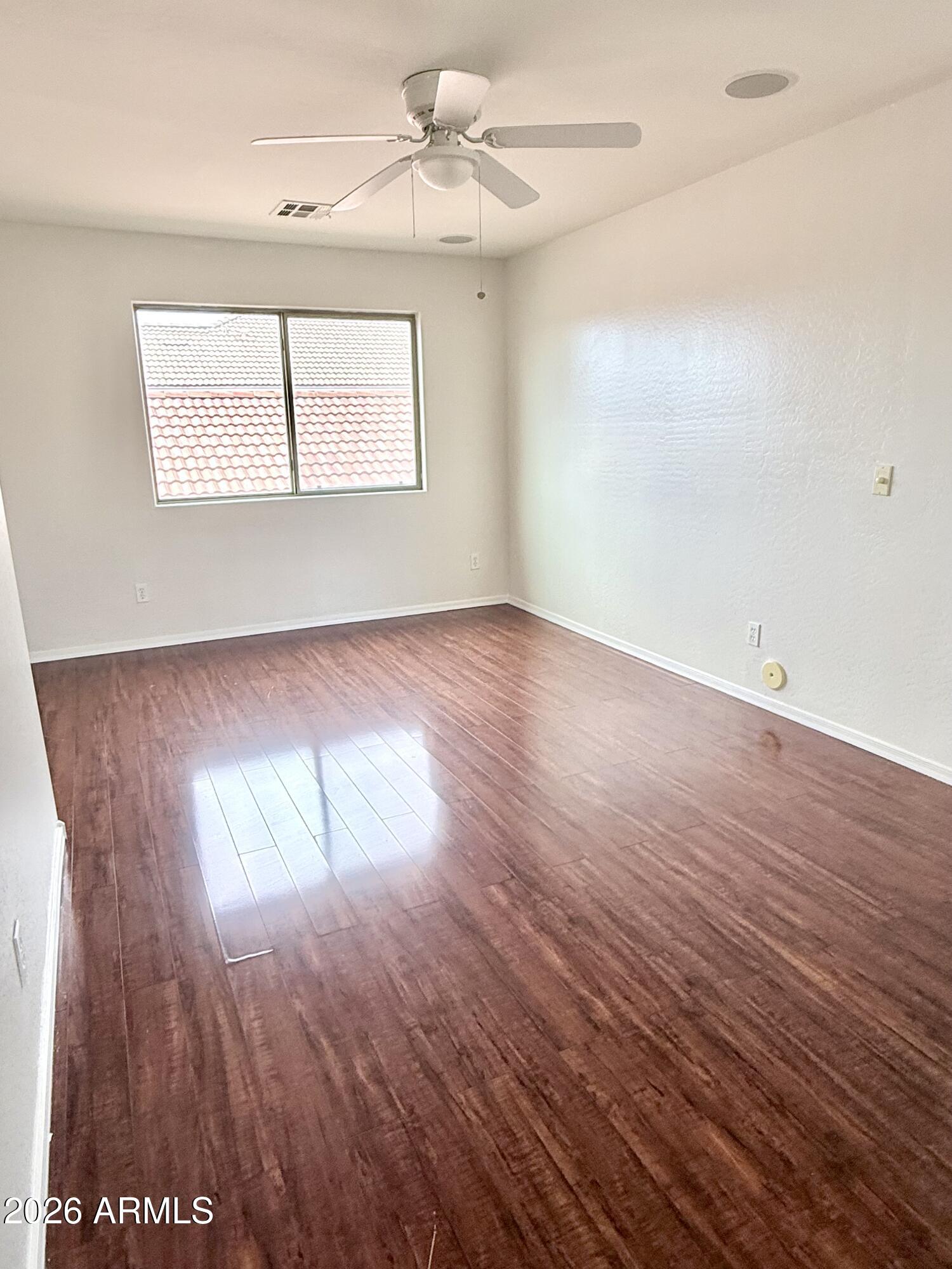 2326 West Gaby Road Phoenix, AZ 85041 - Photo 58 of 75 an empty room with wooden floor chandelier fan and windows