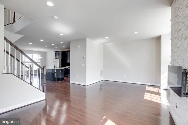 an empty room with wooden floor and a kitchen view