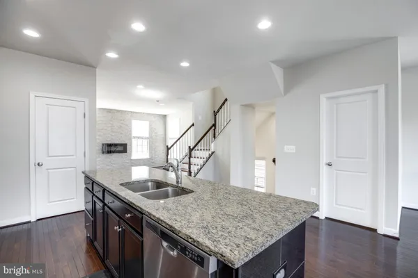 a kitchen with granite countertop a sink and a wooden floor