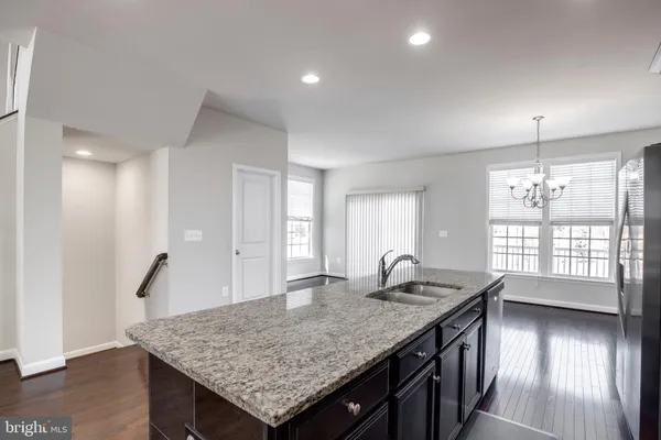 a kitchen with granite countertop kitchen island a sink stove and wooden floor
