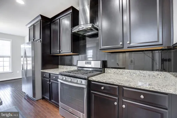 a kitchen with granite countertop a stove and a wooden floors