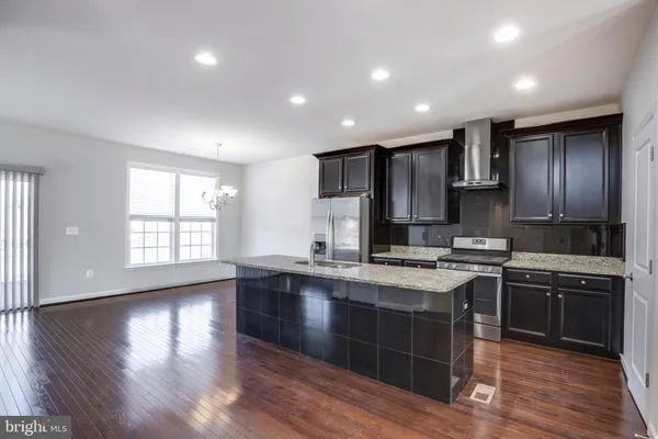 a kitchen with stainless steel appliances granite countertop a stove a sink dishwasher a refrigerator and white cabinets with wooden floor