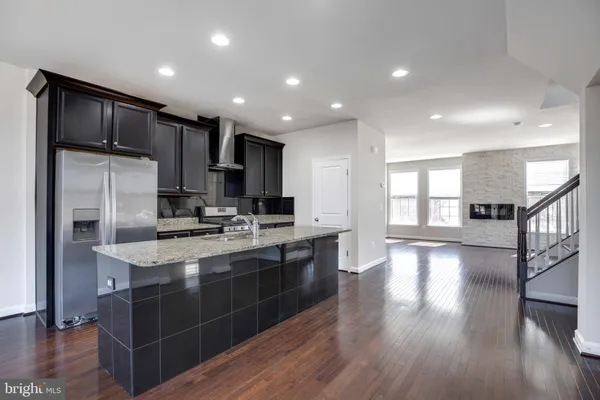 a kitchen with stainless steel appliances kitchen island granite countertop a stove a refrigerator and a sink with wooden floor