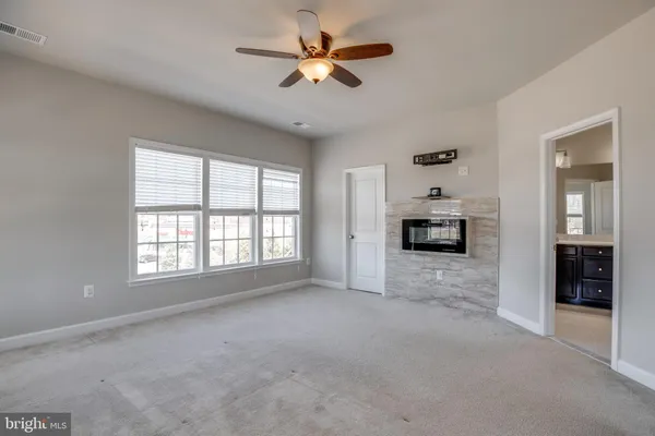 a view of an empty room with a window and a kitchen