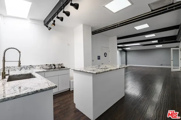 a kitchen with granite countertop a sink cabinets and wooden floor