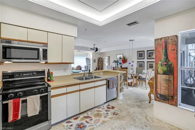 a kitchen with stainless steel appliances granite countertop a stove top oven a sink a dining table and chairs with white cabinets