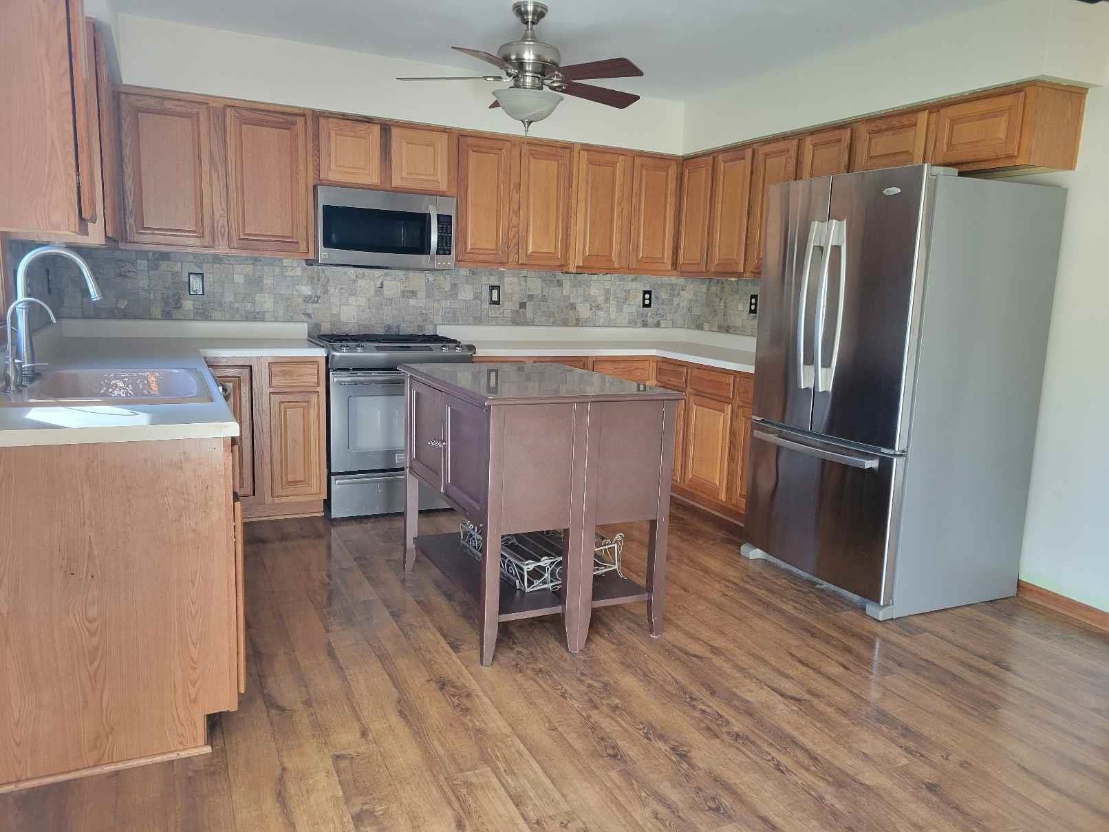1126 Old Hunter Run Byron, IL 61010 - Photo 11 of 24 a kitchen with stainless steel appliances granite countertop a refrigerator a stove a sink a dining table and chairs with wooden floor