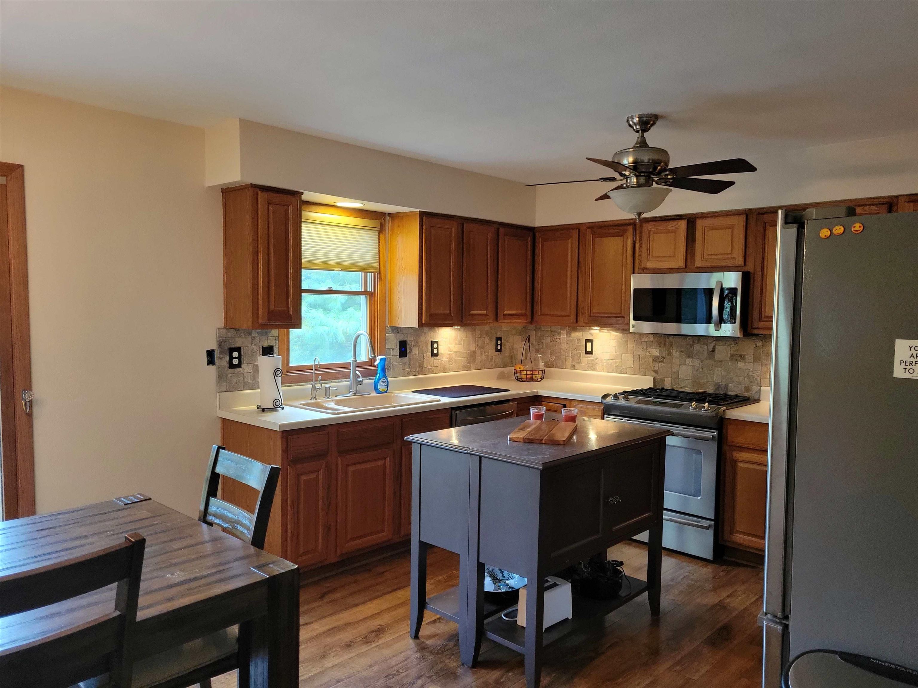 1126 Old Hunter Run Byron, IL 61010 - Photo 8 of 24 a kitchen with stainless steel appliances granite countertop a stove a sink dishwasher a stove a refrigerator a dining table and chairs with wooden floor