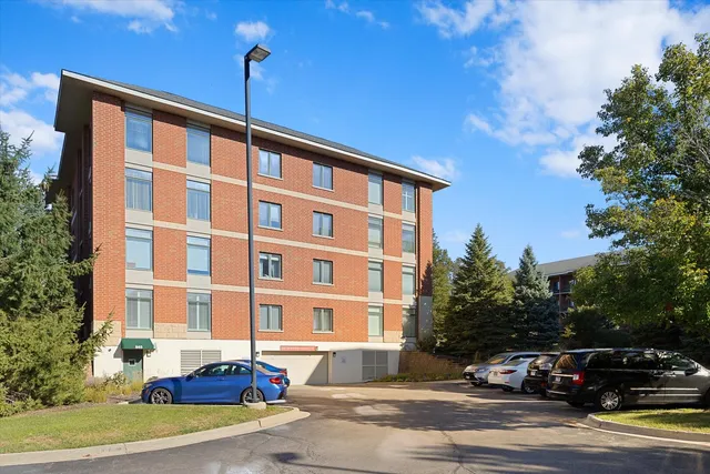 a front view of a building with lot of cars and trees