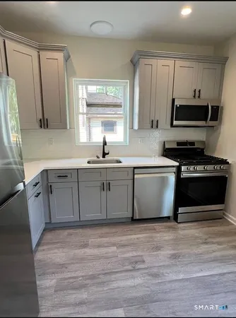 a kitchen with stainless steel appliances granite countertop a sink a stove a refrigerator and cabinets