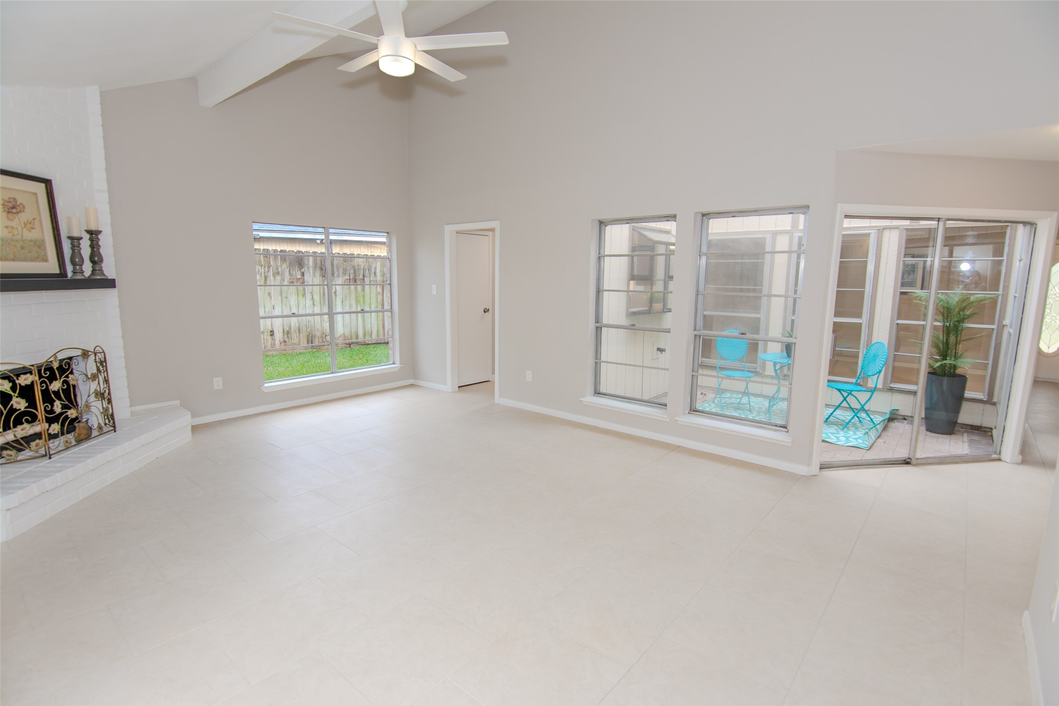 6703 Stonewater Houston, TX 77084 - Photo 12 of 30 Spacious living room with high ceilings, neutral tile flooring, and a ceiling fan. Features a cozy fireplace, large windows for natural light, and bright patio area.