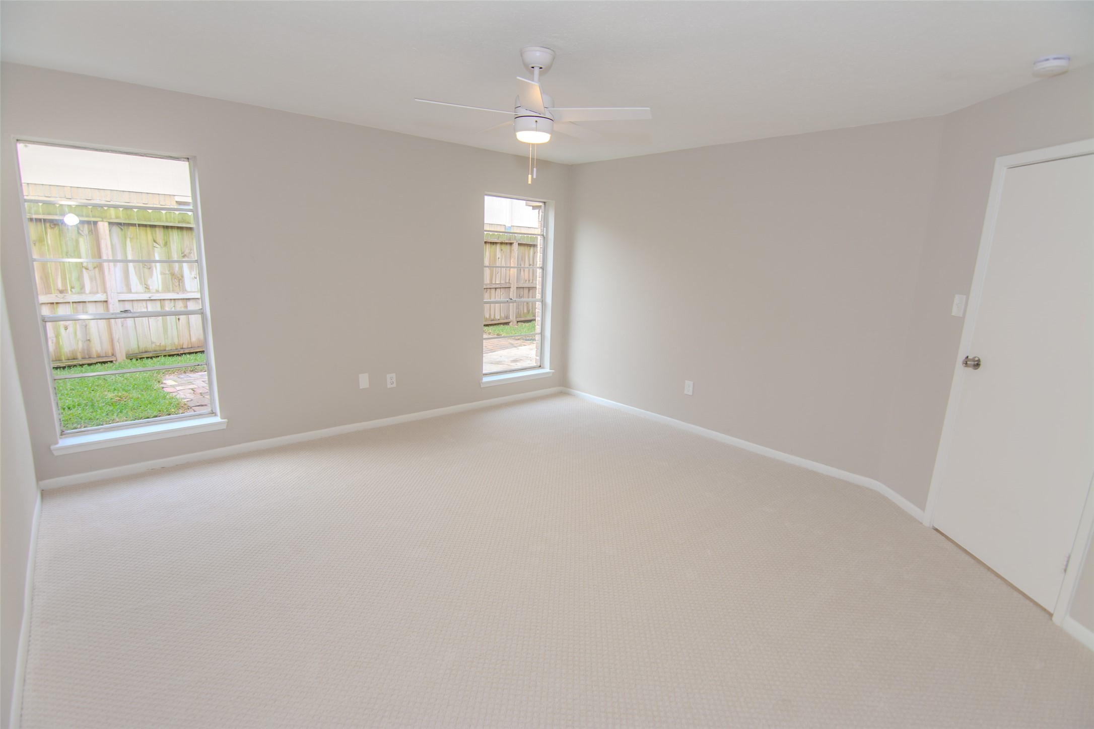 6703 Stonewater Houston, TX 77084 - Photo 17 of 30 Another view of your primary bedroom features neutral walls, designer carpeting, and two large windows offering natural light and a view of the fenced backyard.