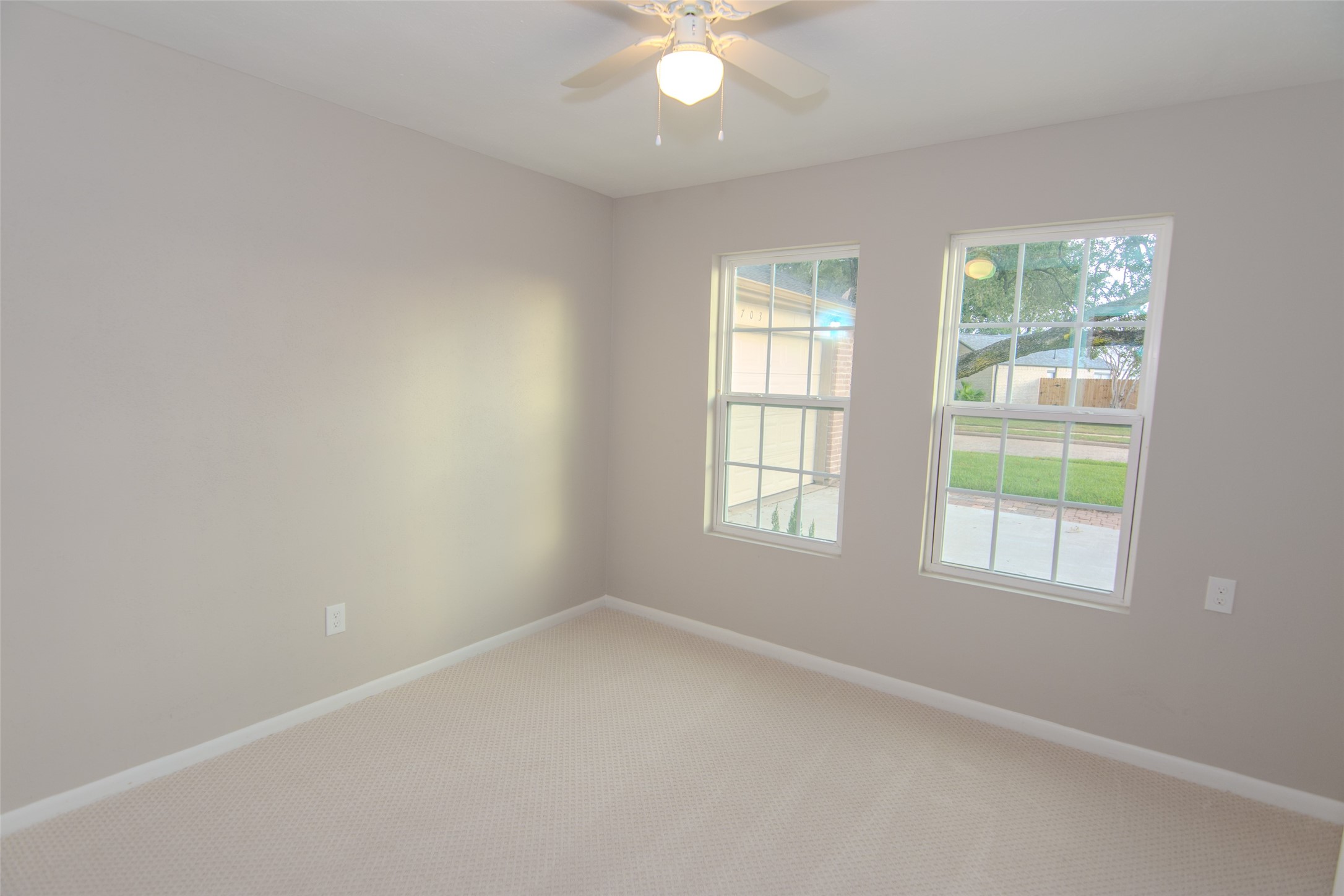 6703 Stonewater Houston, TX 77084 - Photo 20 of 30 Bedroom 2 features neutral walls, a ceiling fan, and two large windows providing natural light, ideal for a cozy bedroom or office space.