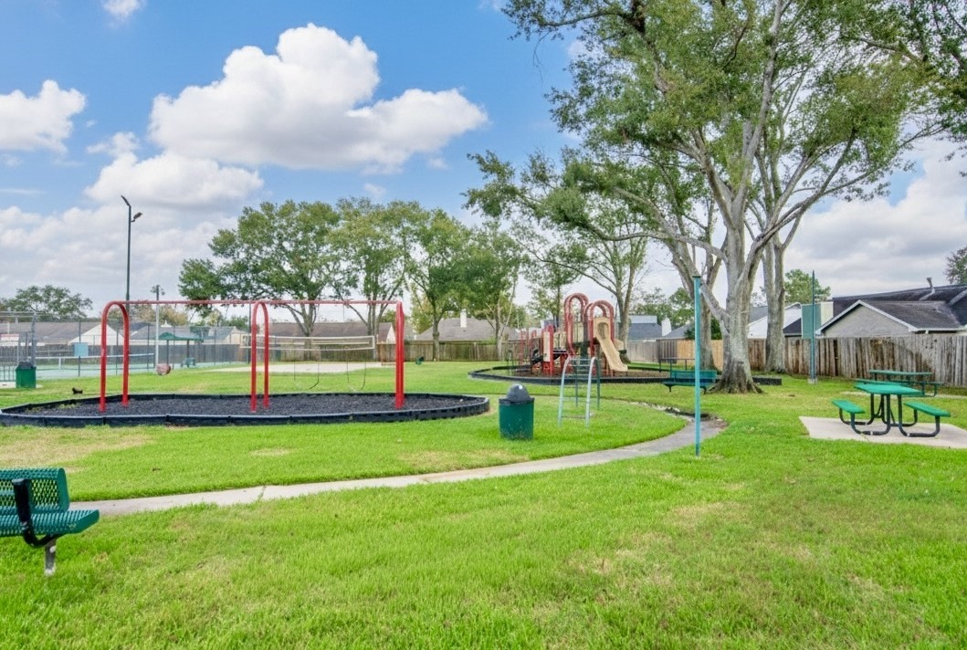 6703 Stonewater Houston, TX 77084 - Photo 28 of 30 Playground and a sand volleyball court, perfect for family activities and entertaining. The area is surrounded by mature trees and enclosed with a wooden fence, offering privacy and charm.