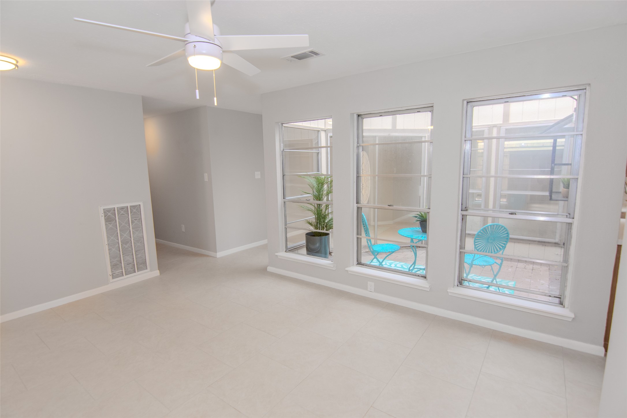 6703 Stonewater Houston, TX 77084 - Photo 9 of 30 Dining room offers large windows overlooking a small patio area. Features a ceiling fan and light neutral tile flooring, offering a clean and modern feel.