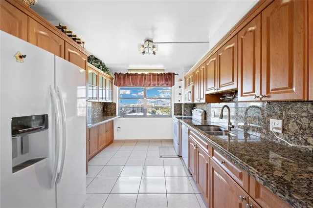 a kitchen with stainless steel appliances granite countertop a refrigerator a stove and a sink