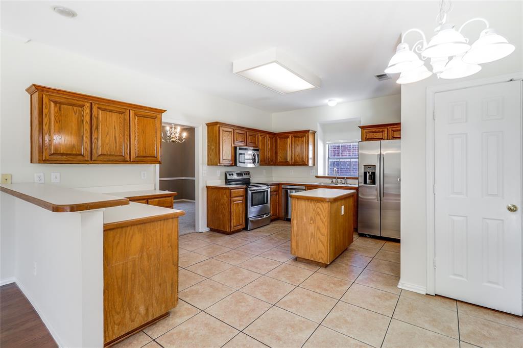 8100 Steamers Lane Frisco, TX 75035 - Photo 11 of 24 a kitchen with a refrigerator a stove top oven and a dishwasher
