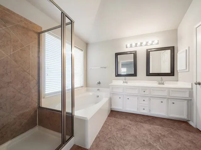 a spacious bathroom with a double vanity sink a mirror and a bathtub