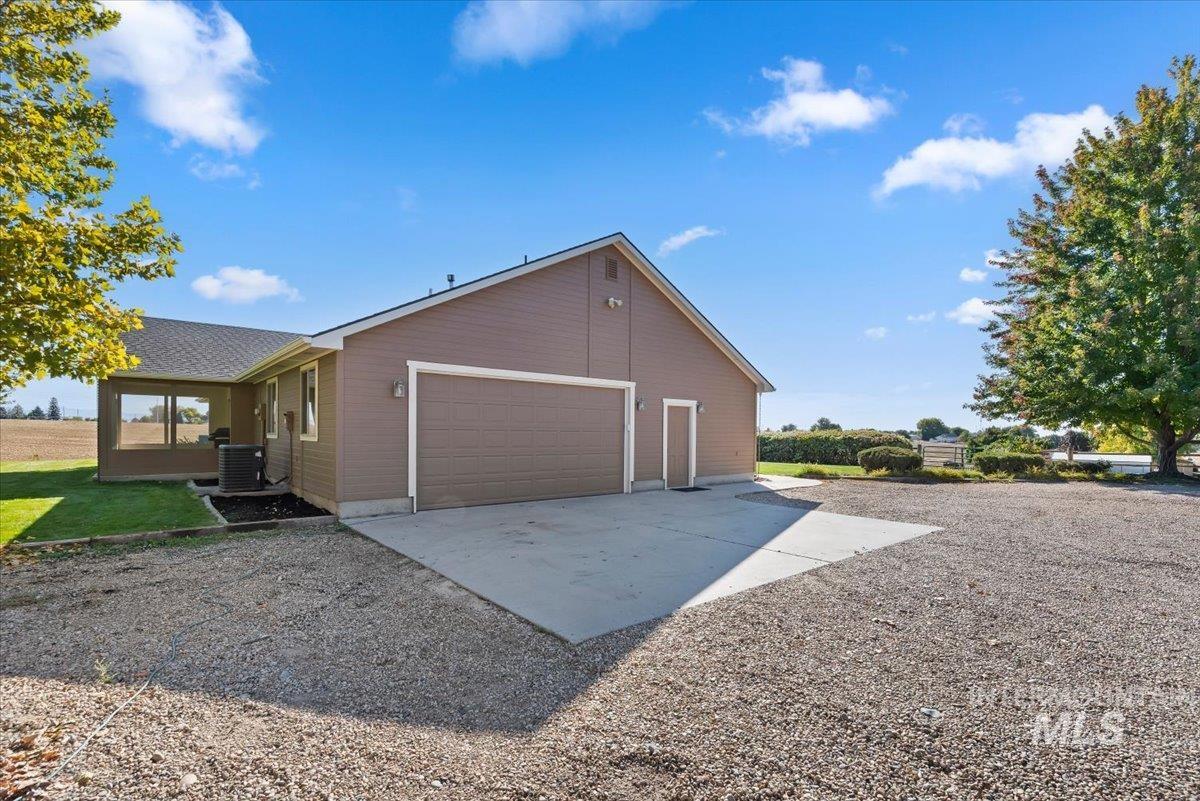 24240 Tiger Lane Caldwell, ID 83607 - Photo 35 of 50 Attached two-car garage with a concrete driveway and gravel parking area