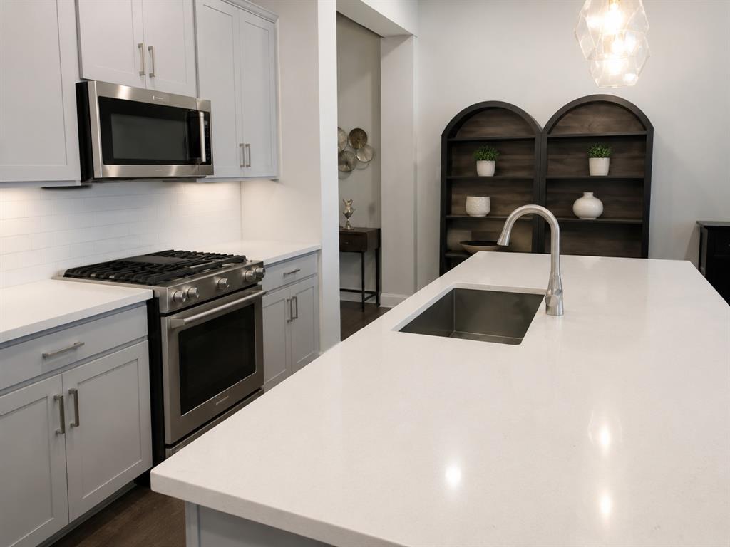 8235 Snapdragon Way Dallas, TX 75252 - Photo 8 of 29 Kitchen island featuring an undermount stainless steel sink, gooseneck faucet, and light-toned countertop