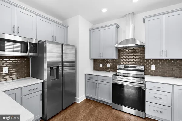 a kitchen with cabinets stainless steel appliances and wooden floor