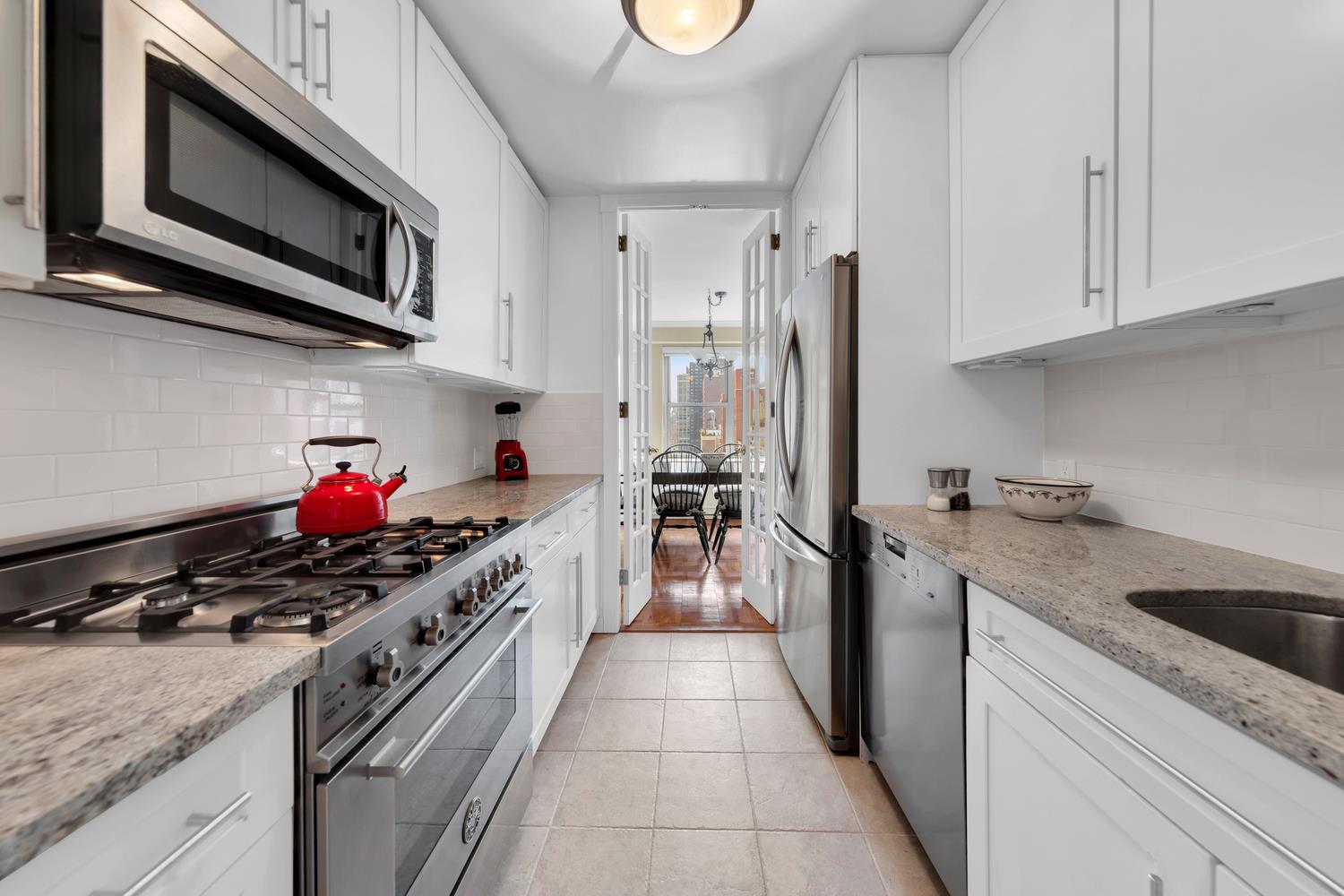 360 East 72nd Street, Unit C2205 Manhattan, NY 10021 - Photo 8 of 16 a kitchen with stainless steel appliances granite countertop a stove and a sink