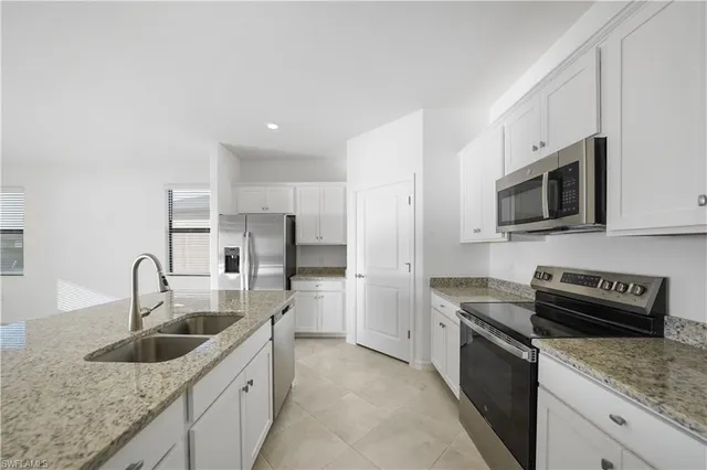 a large white kitchen with a large window appliances and cabinets