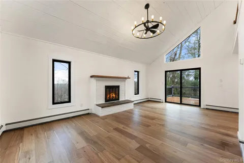 a view of an empty room with wooden floor fireplace and a window