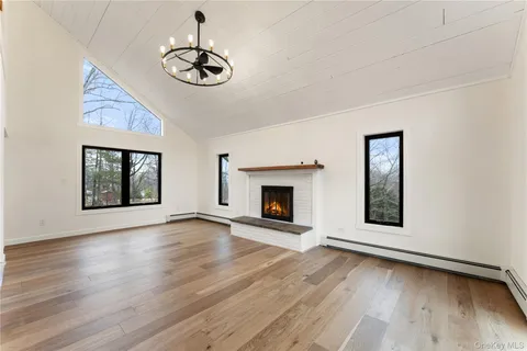 a view of an empty room with wooden floor fireplace and a window