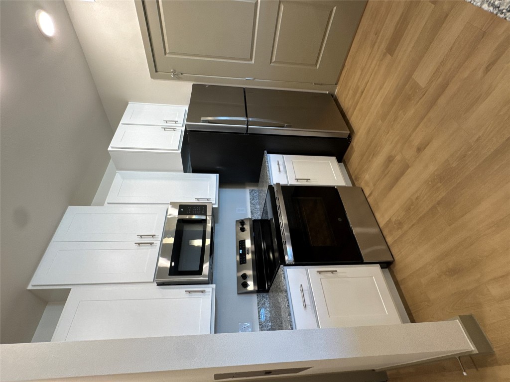 691 Union Chapel Road, Unit B2 Cedar Creek, TX 78612 - Photo 15 of 26 Kitchen featuring stainless steel appliances, stone counters, white cabinetry, and light wood-style flooring