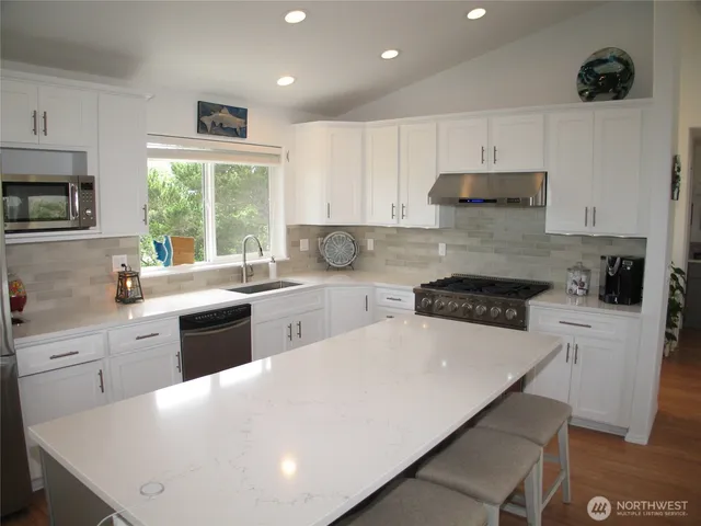 a large white kitchen with wooden floors and stainless steel appliances