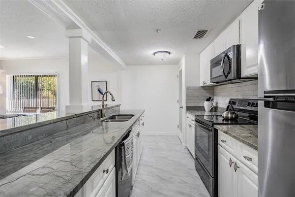 a kitchen with stainless steel appliances granite countertop a refrigerator a stove top oven a sink and dishwasher