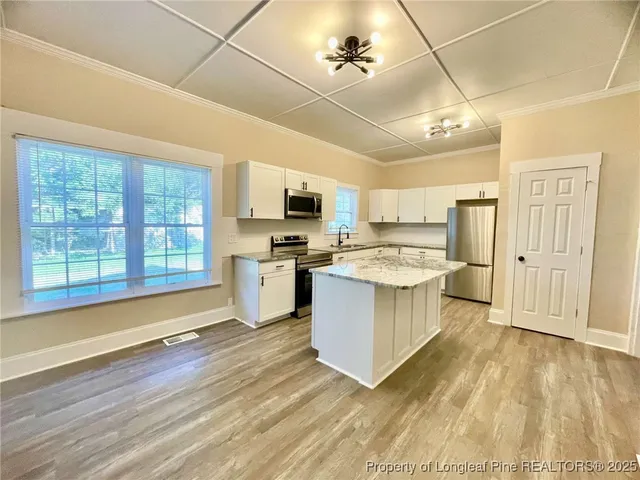 a large kitchen with cabinets wooden floor and stainless steel appliances