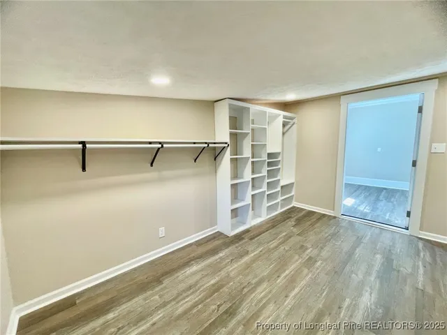 an empty room with wooden floor closet and windows