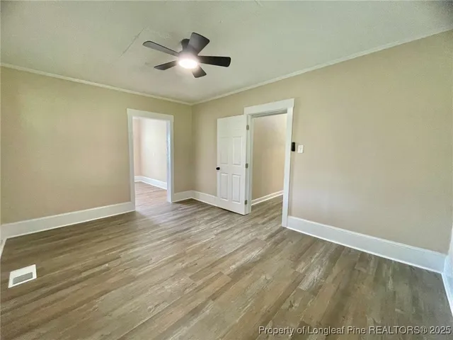 an empty room with wooden floor and a ceiling fan