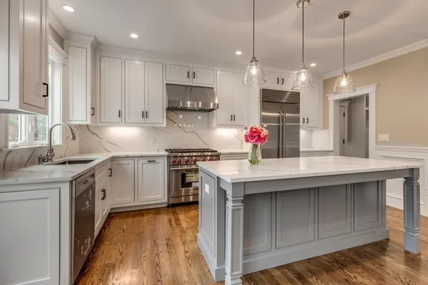 a kitchen with kitchen island granite countertop a sink a counter space appliances and cabinets