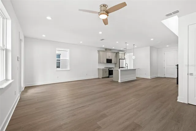 a view of kitchen and empty room with wooden floor and windows
