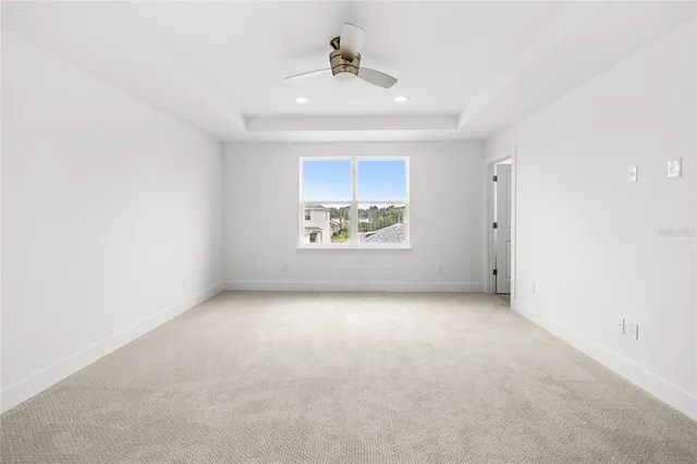 an empty room with windows and ceiling fan
